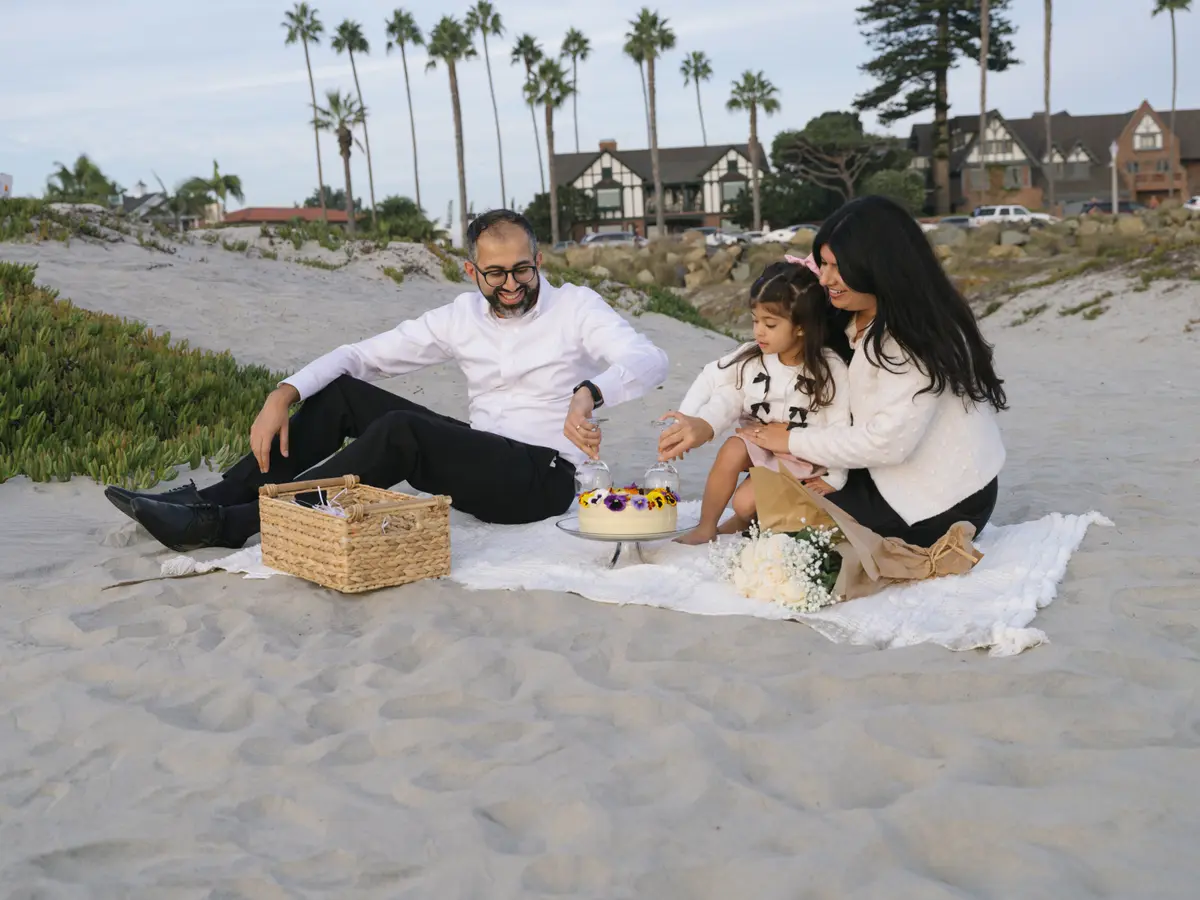 Family celebrating with a cake picnic on the sand near Coronado’s beach homes