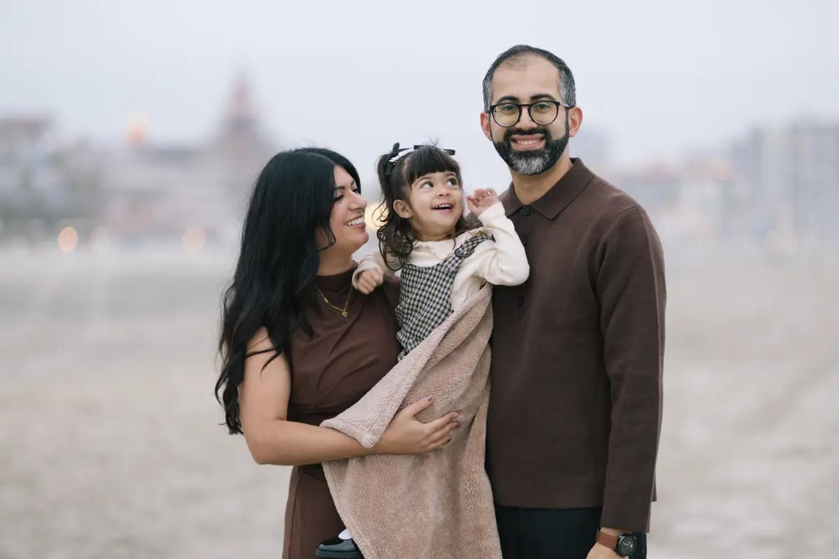 Family of three cuddled in a blanket on Coronado Beach