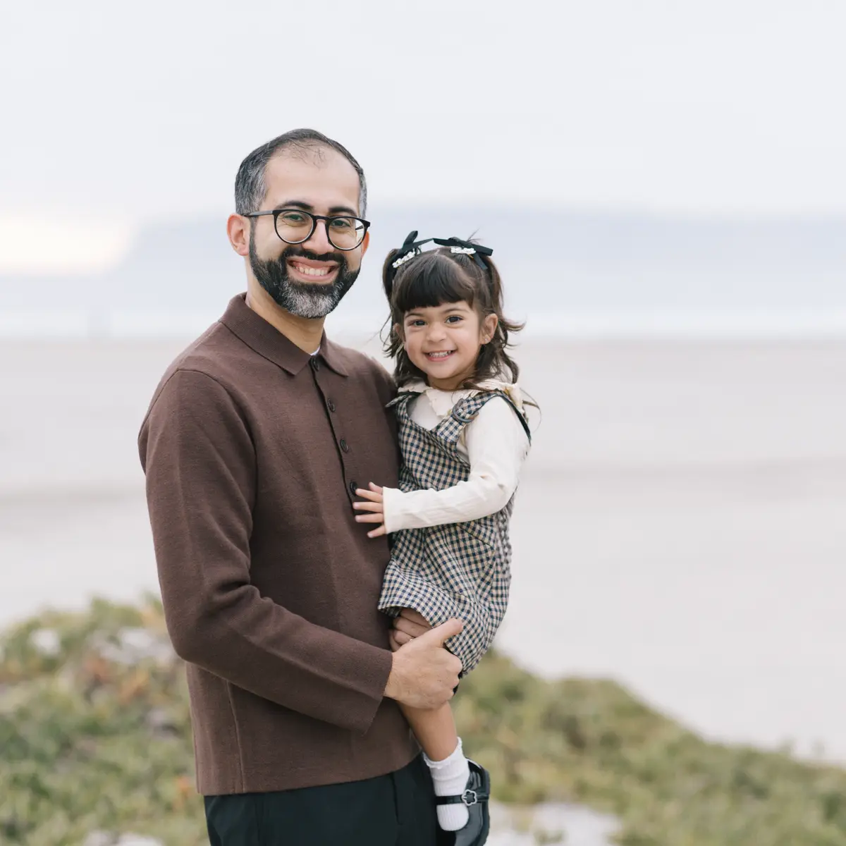 Dad holding his smiling daughter above the dunes in Coronado