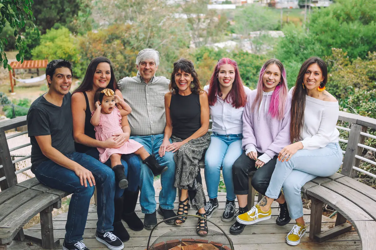 Extended family gathered on a curved backyard bench for their holiday portrait