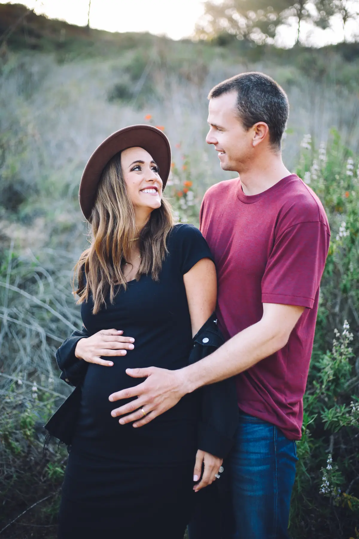 Expecting couple embracing on a wildflower hillside during their maternity session