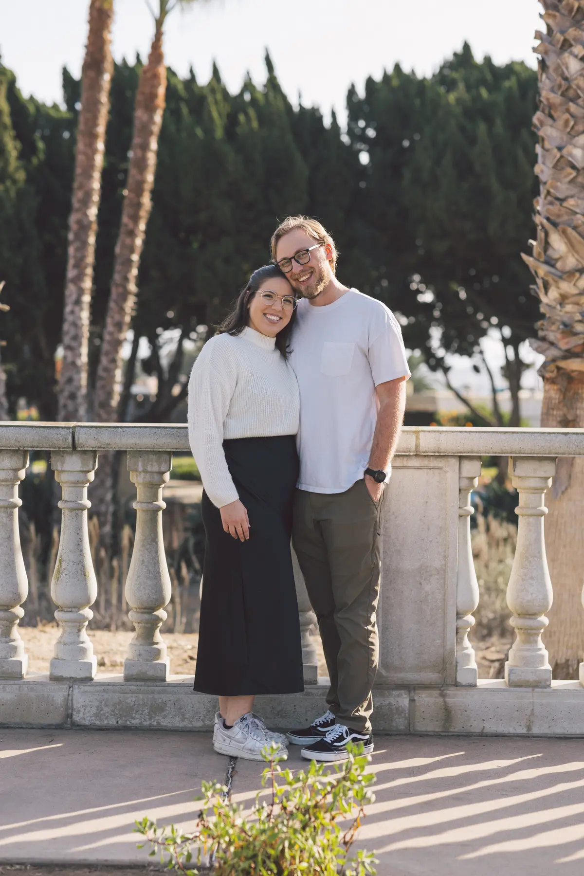 Couple standing together at a stone balustrade framed by palm trees