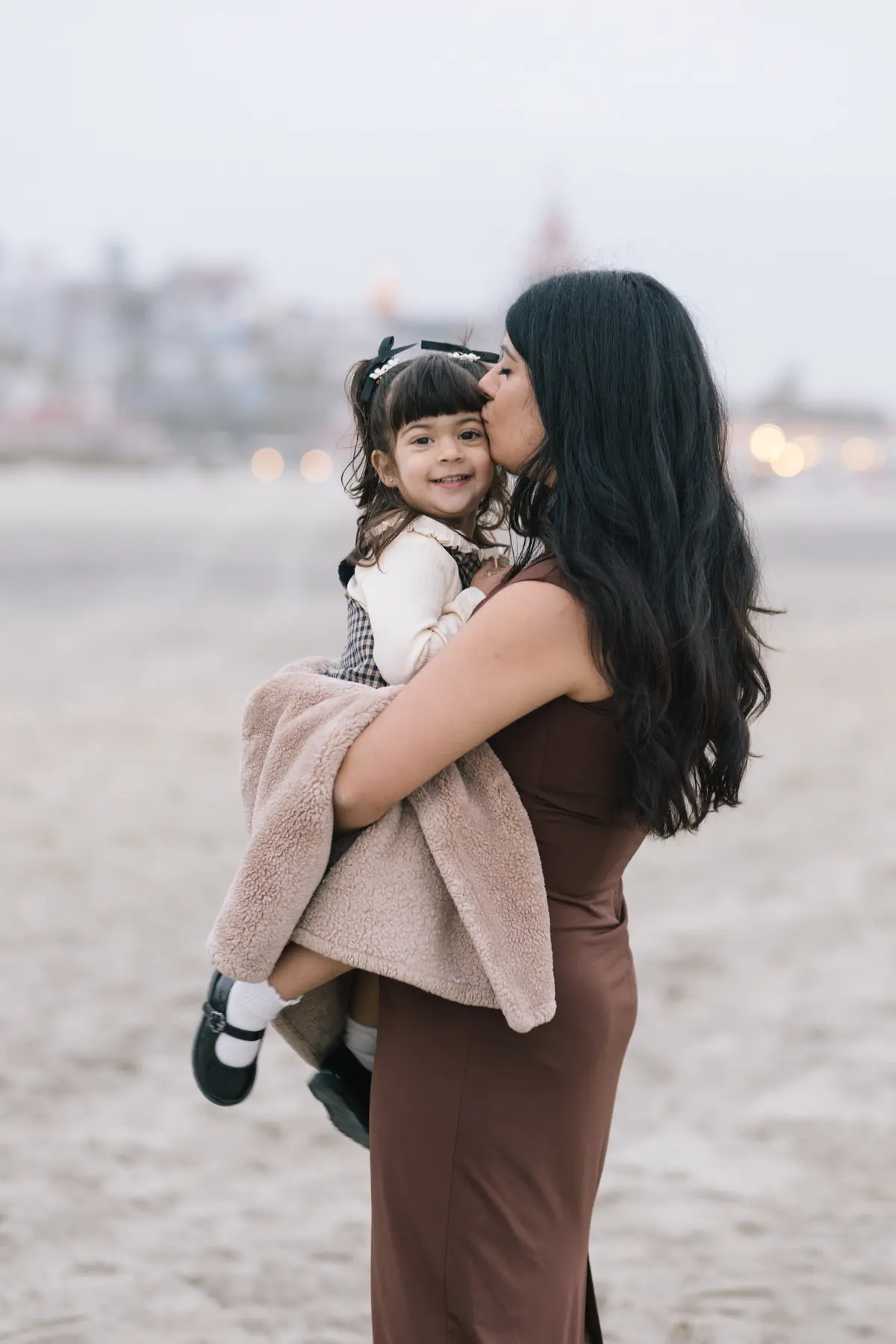Mom kissing her daughter’s cheek on the beach in Coronado