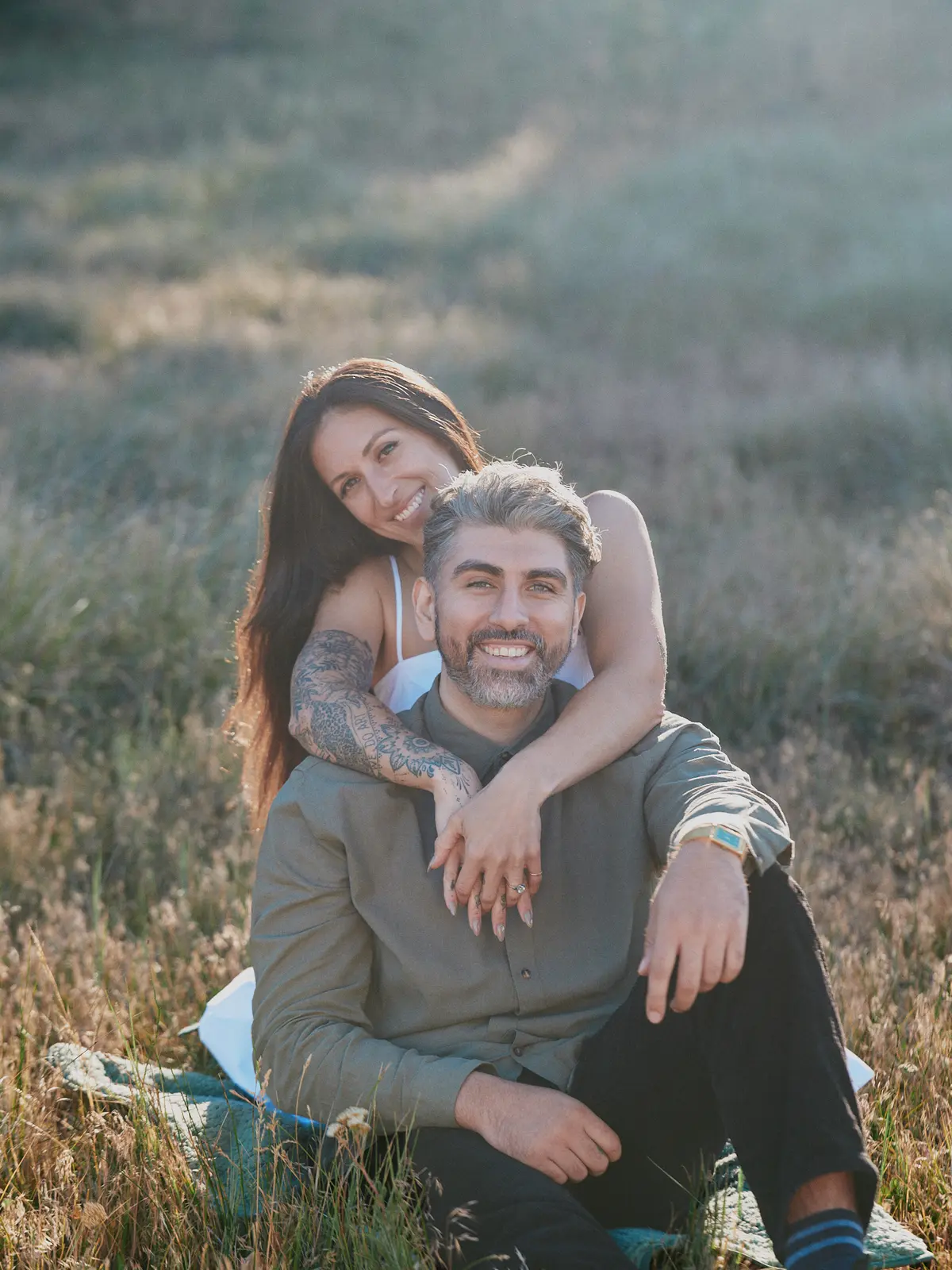 Engaged couple laughing together in a golden meadow