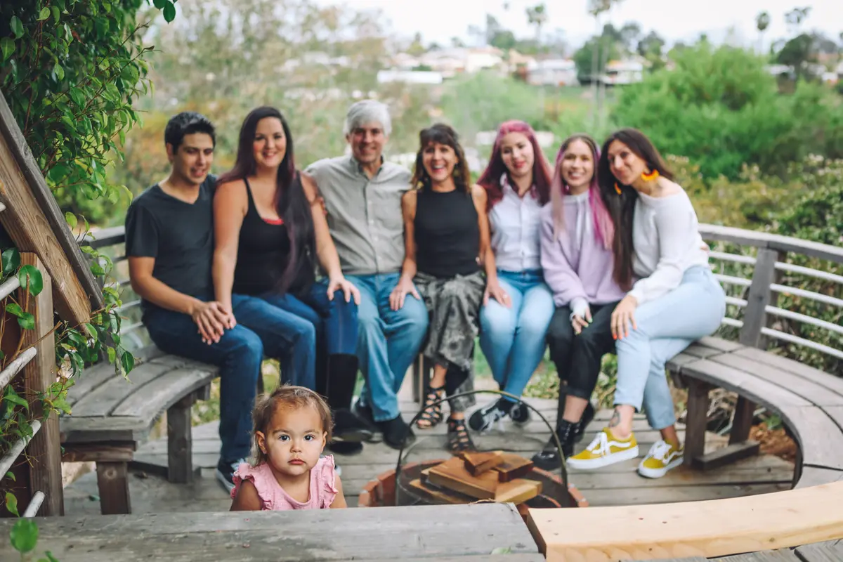 Toddler peeking into the frame in front of her extended family